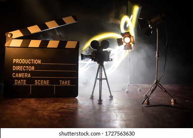 Movie concept. Miniature movie set on dark toned background with fog and empty space. Silhouette of vintage camera on tripod and clapboard. Selective focus - Shutterstock ID 1727563630