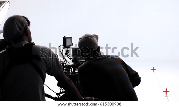 Movie director and photographer are\
talking or consulting to making studio set before shooting video\
production and silhouette background\
lighting.