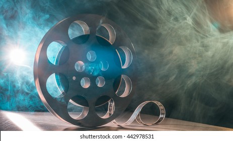 Movie reel of film in retro in the smoke of green and blueon a dark background - Powered by Shutterstock