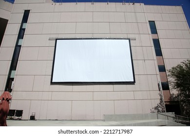 Movie Screen. An Outdoor Theater Screen Or Movie Screen Attached To A Tall Building. A Projection Screen For A Movie Or Slideshow Presentation On A Building Wall. Outdoor Presentation On A Wall.