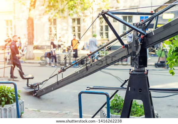 Movie set with\
professional equipment and media production team on city street.\
Outdoor film making. Big camera crane with cameraman seat at open\
air cinema  making scene