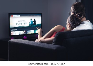 Movie stream service on smart tv. Couple watching series online. Woman choosing film or new season with remote control. Video on demand (VOD) site mockup on screen. Digital streaming network.