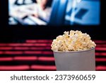 Movies and popcorn. Pop corn at cinema. Family film night concept. Action or romantic comedy entertainment on screen. Dark theater with red seats. Salty snack in bucket or box. Spectator or critic pov