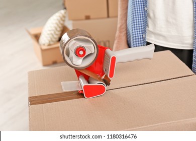 Moving box and adhesive tape dispenser indoors, closeup - Shutterstock ID 1180316476