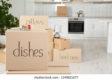 Moving boxes and adhesive tape dispenser in kitchen. Space for text - Shutterstock ID 1190821477