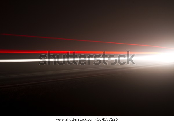 Moving car\
lights in a fog at night on a dark\
road