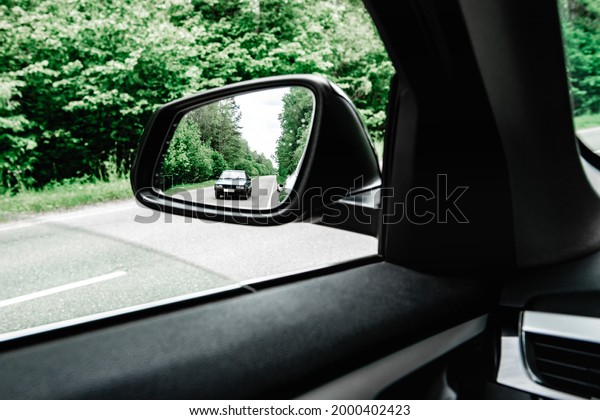 Moving car in
side rear-view mirror of modern
car.