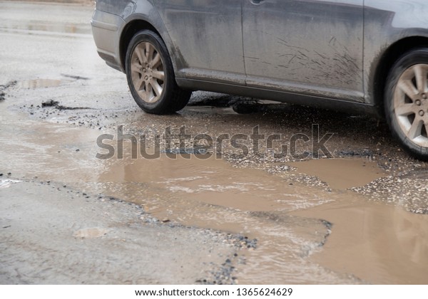 Moving car sprays puddle when heavy rain drops\
on concrete.