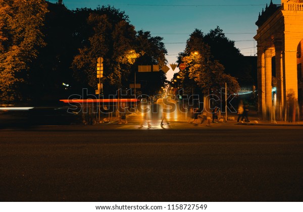 Moving cars on the night city. Blurred cars and\
people walking