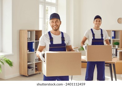 Moving company workers in uniforms take parcels from a modern office. Two happy, cheerful, smiling men from the delivery service carry cardboard boxes to load in their van - Powered by Shutterstock