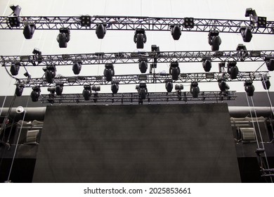 Moving head spotlight devices are clamped on a rigging steel trusses. Video led screen. Installation of professional lighting equipment for a concert.