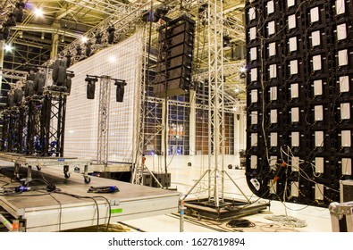 Moving head spotlight devices on a truss. Line array speakers. Big led screen. Installation of professional stage, sound, light and video equipment for a concert.