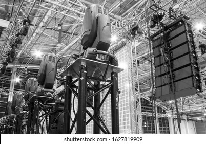 Moving head spotlight devices on a truss. Line array speakers. Installation of professional stage, sound and light equipment for a concert. - Shutterstock ID 1627819909