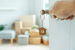Moving House, Relocation. The Key Was Inserted Into The Door Of The New House, Inside The Room Was A Cardboard Box Containing Personal Belongings And Furniture. Move In The Apartment Or Condominium