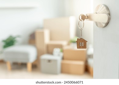 Moving house, relocation. The key was inserted into the door of the new house, inside the room was a cardboard box containing personal belongings and furniture. move in the apartment or condominium - Powered by Shutterstock