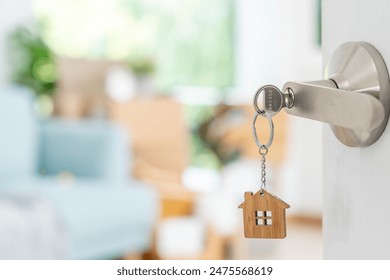 Moving house, relocation. The key was inserted into the door of the new house, inside the room was a cardboard box containing personal belongings and furniture. move in the apartment or condominium - Powered by Shutterstock