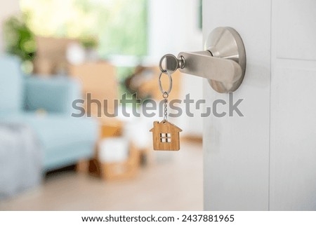 Moving house, relocation. The key was inserted into the door of the new house, inside the room was a cardboard box containing personal belongings and furniture. move in the apartment or condominium