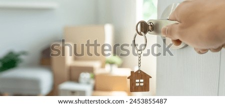 Moving house, relocation. The key was inserted into the door of the new house, inside the room was a cardboard box containing personal belongings and furniture. move in the apartment, banner