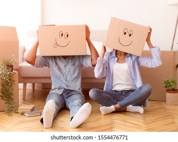 Moving House. Unrecognizable Couple With Cardboard Boxes With Smiley Faces On Head Sitting On Floor Having Fun In New Apartment - Powered by Shutterstock