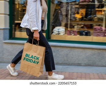 Moving image of a girl walking hurriedly with a shopping bag in front of a shop window. Shopping day, bargains, black friday.