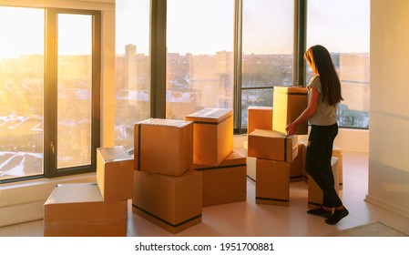 Moving into new home movers pick-up service. Woman ready to move from apartment with belongings packed in many cardboard boxes packages for shipping.