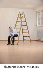 Moving To New Office Or House: Man Sitting On Ladder In Empty Room