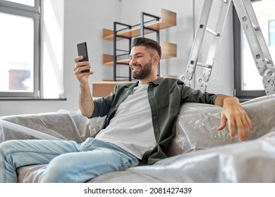 Moving, People And Real Estate Concept - Happy Smiling Man With Smartphone At New Home