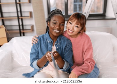 Moving, People And Real Estate Concept - Happy Smiling Women With Selfie Stick Taking Picture At New Home