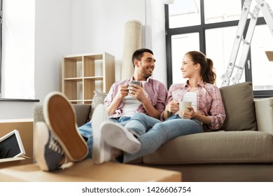 moving, people, repair and real estate concept - happy couple sitting on sofa and drinking coffee at new home - Shutterstock ID 1426606754