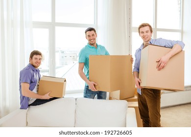 Moving, Real Estate And Friendship Concept - Smiling Male Friends Carrying Boxes At New Place