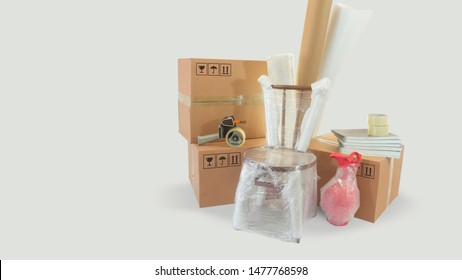 Moving Scene With A Chair And Vase Packed In Plastic Bubble With Closed Cardboard Boxes And Rolls Of Plastic And Foam To Pack On White Background