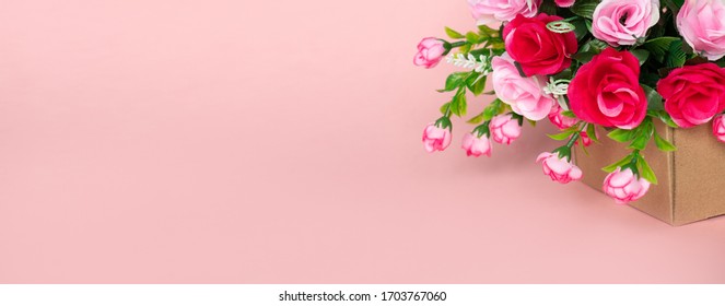 Moving Single Cardboard Box With A Bouquet Of Red And Pink Beautiful Bright Roses On A Pink Background As A Gift For A Wedding, Valentine's Day Or March 8 To A Woman: Flower Shop Concept, Delivery