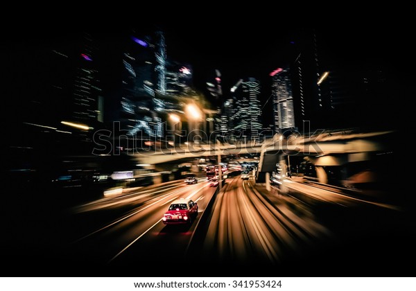 Moving through modern city\
street with illuminated skyscrapers. Hong Kong. Abstract cityscape\
traffic background with taxi car driving at night. Motion blur, art\
toning