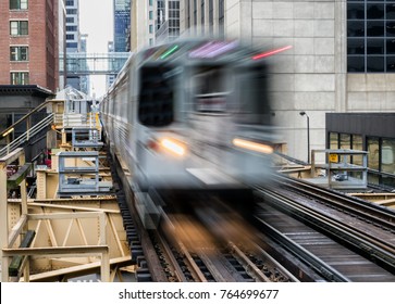 Moving Train on elevated tracks within buildings at the Loop, Glass and Steel bridge between buildings - Chicago City Center - Long Exposure - Chicago, Illinois, USA