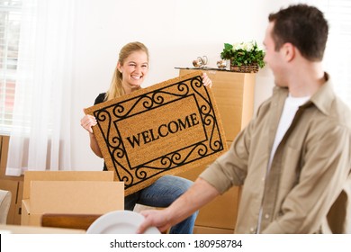Moving: Woman Holds Up Welcome Mat After Unpacking