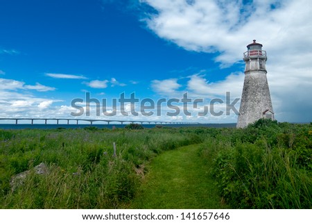 A mowed path leads you to the lighthouse through the wild meadow with the Confederation Bridge to PEI in the background. Cape Jourimain National Wildlife Area, Bayfield, New Brunswick, Canada.