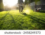 Mowing the grass with a lawn mower. Garden work concept background.