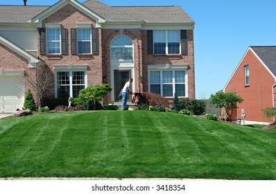 Mowing The Lawn - Professional Lawn Care Company Personnel Using A Riding Lawn Mower To Cut The Grass.