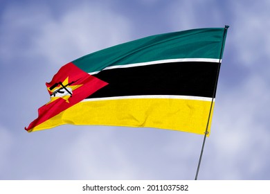 Mozambique flag isolated on sky background. National symbol of Mozambique. Close up waving flag with clipping path.