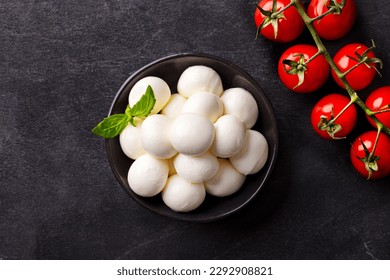 Mozzarella cheese balls with tomatoes and basil. Dark slate background. Top view.