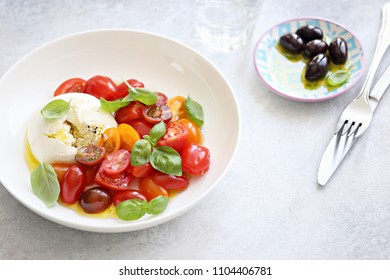 Mozzarella and cherry tomatoes salad with fresh basil and olives.  - Shutterstock ID 1104406781