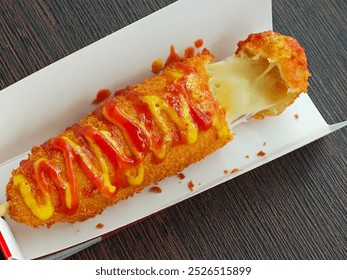 Mozzarella corn dog with the tip cut off to reveal melted cheese on the inside. South Korean street food. Cheese wrapped in flour batter, fried and drizzled with mustard and tomato ketchup - Powered by Shutterstock