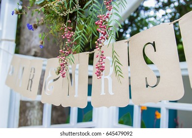 Mr and Mrs brown die cut wedding garland sign on string under arch with flowers - Shutterstock ID 645479092