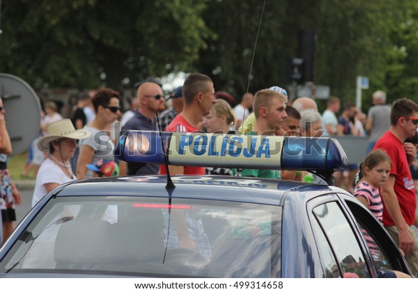 Mragowo, Poland,  festival Piknik Country &\
Folk Mragowo, parade vehicles, July 31, 2016:Police blue lights\
mounted on the roof of Polish police car in the background a crowd\
of people walking.