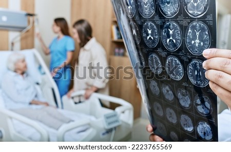MRI of head of elderly woman in hands of doctor standing in medical ward near senior patient with relative and nurse. Recovery after a stroke