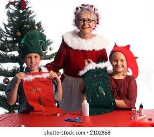  Mrs. Santa Claus With A Pair Of Proud Young Elves Showing Off Their Hand Crafted Christmas Stockings