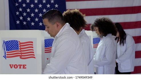 MS Group Of Four Scientists Or Doctors Of Various Demographics, All In White Lab Coats, Voting At Booths In Polling Station During US Election