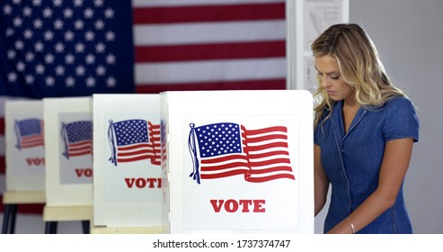 MS Young blonde woman casts votes at booths in polling station with US flag.