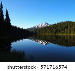 Mt. Bachelor in the Cascade Mountain Range in Central Oregon  reflecting in Todd Lake in the morning summer Iight which also lights up the trees with a nice glow.