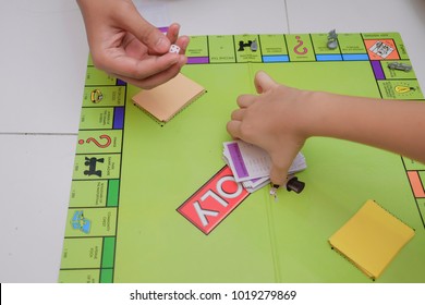 Muadzam Shah, Malaysia - December 3rd, 2017 : Asian Children  Hands Playing Monopoly Game On A Floor. A Board Game In The Genre Of Economic Strategy For Two Or More People.